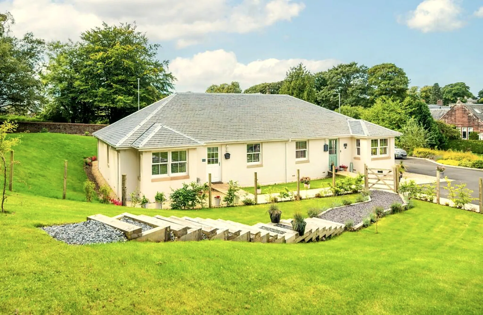 A renovated single-storey Scottish home with cream render and landscaped garden.